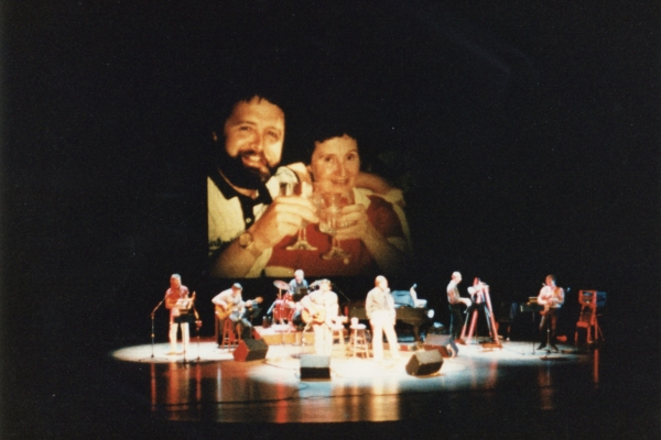 Pearson and McCoy in concert with a photo of Sands and his mother behind them