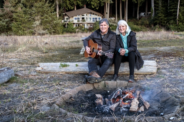 Mark with his guitar and Pat sitting by the fire on the beach