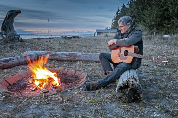 Mark with his guitar sitting by the campfire