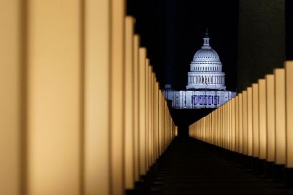 The US Capitol at night with lights in the foreground marking the deaths to Covid