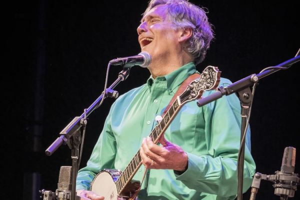 Mark singing spiritedly with banjo on stage