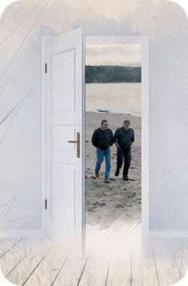 An open doorway showing Mark Pearson and Mike McCoy walking with each other on a beach